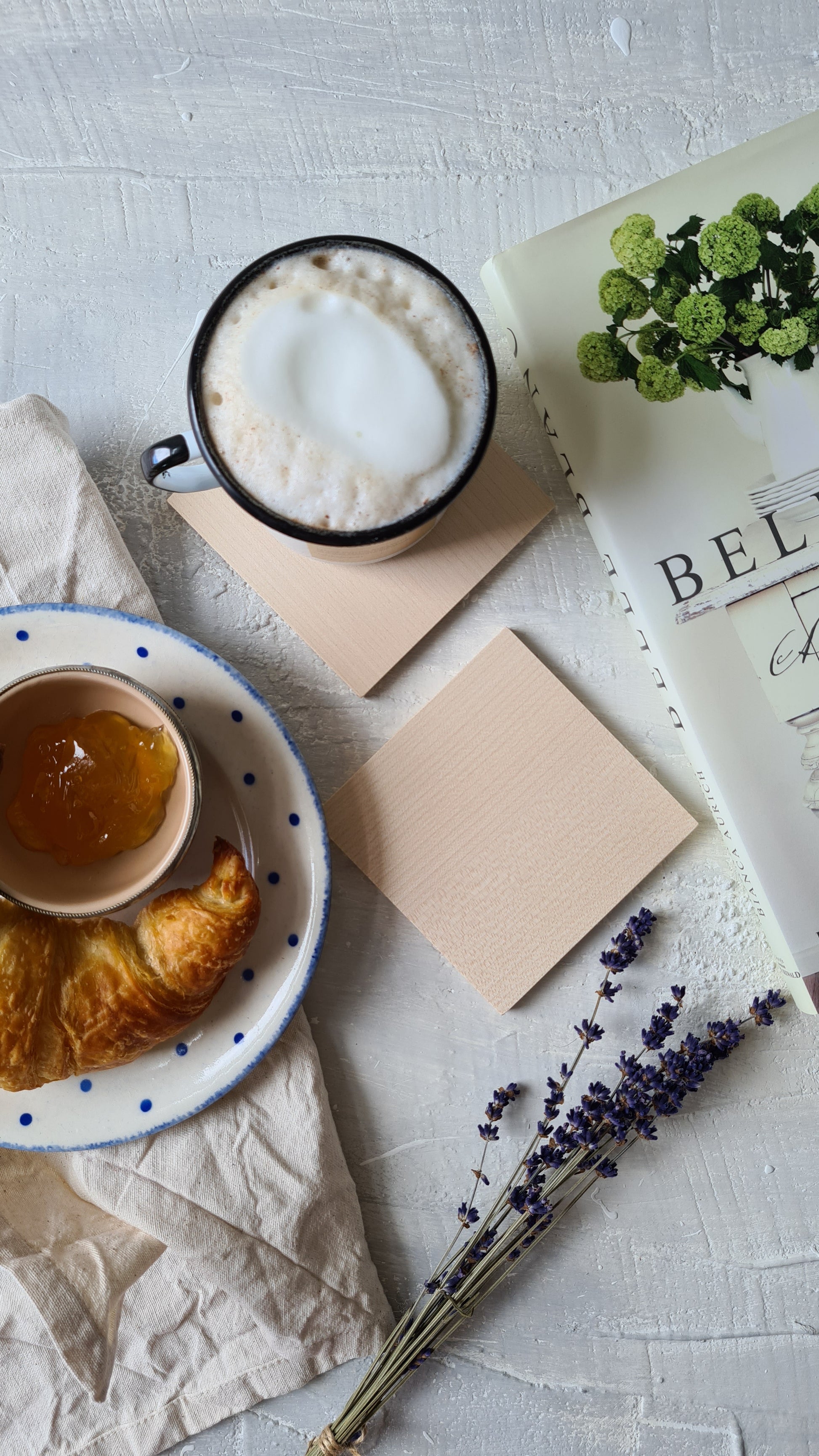 quadratischer Holzuntersetzer dekoriert mit Kaffeetasse und Croissant