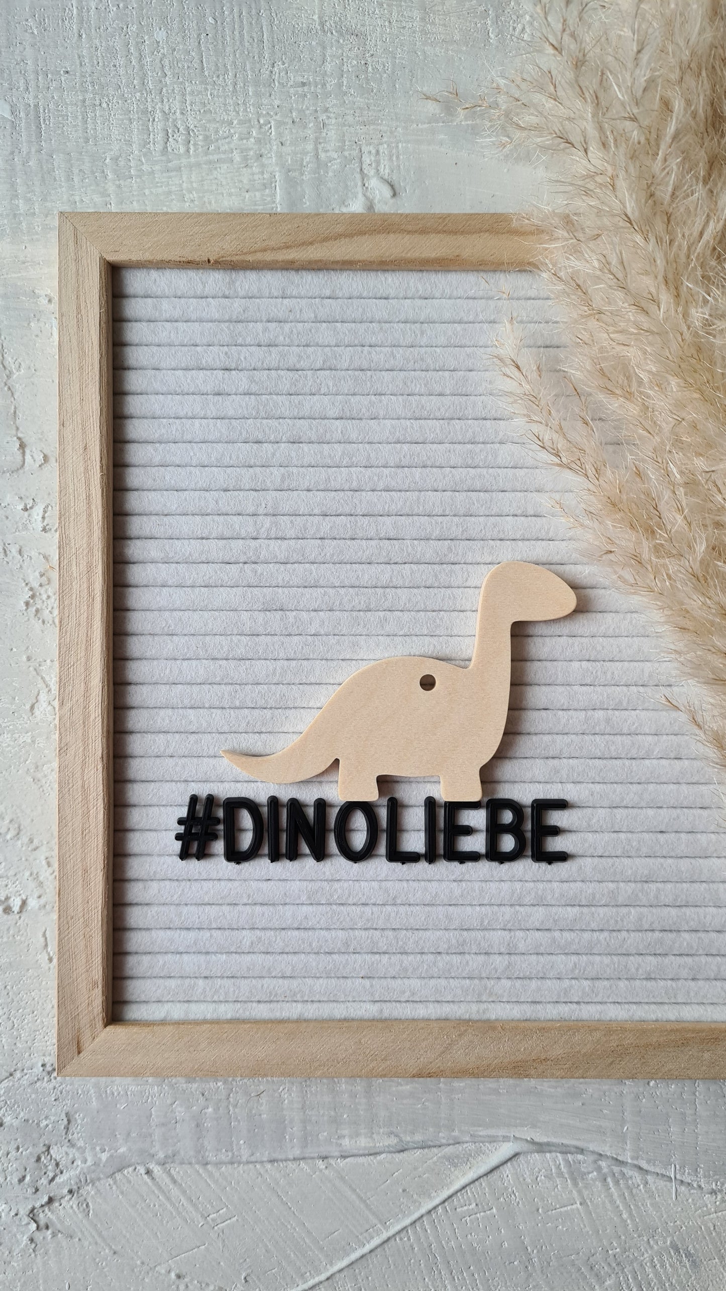 Dino-Anhänger Brontosaurus dekoriert auf Buchstabentafel mit Pampasgras